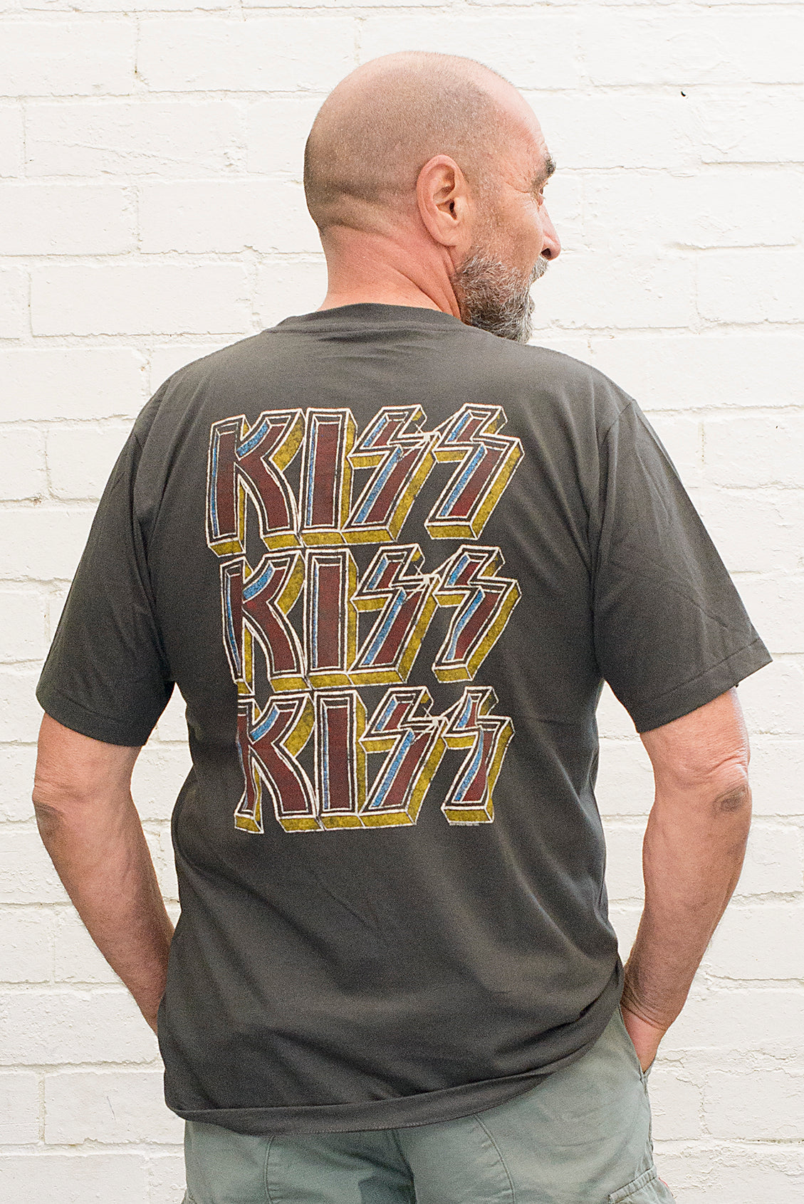 model wearing black cotton t-shirt with kiss logo repeated three times printed on back