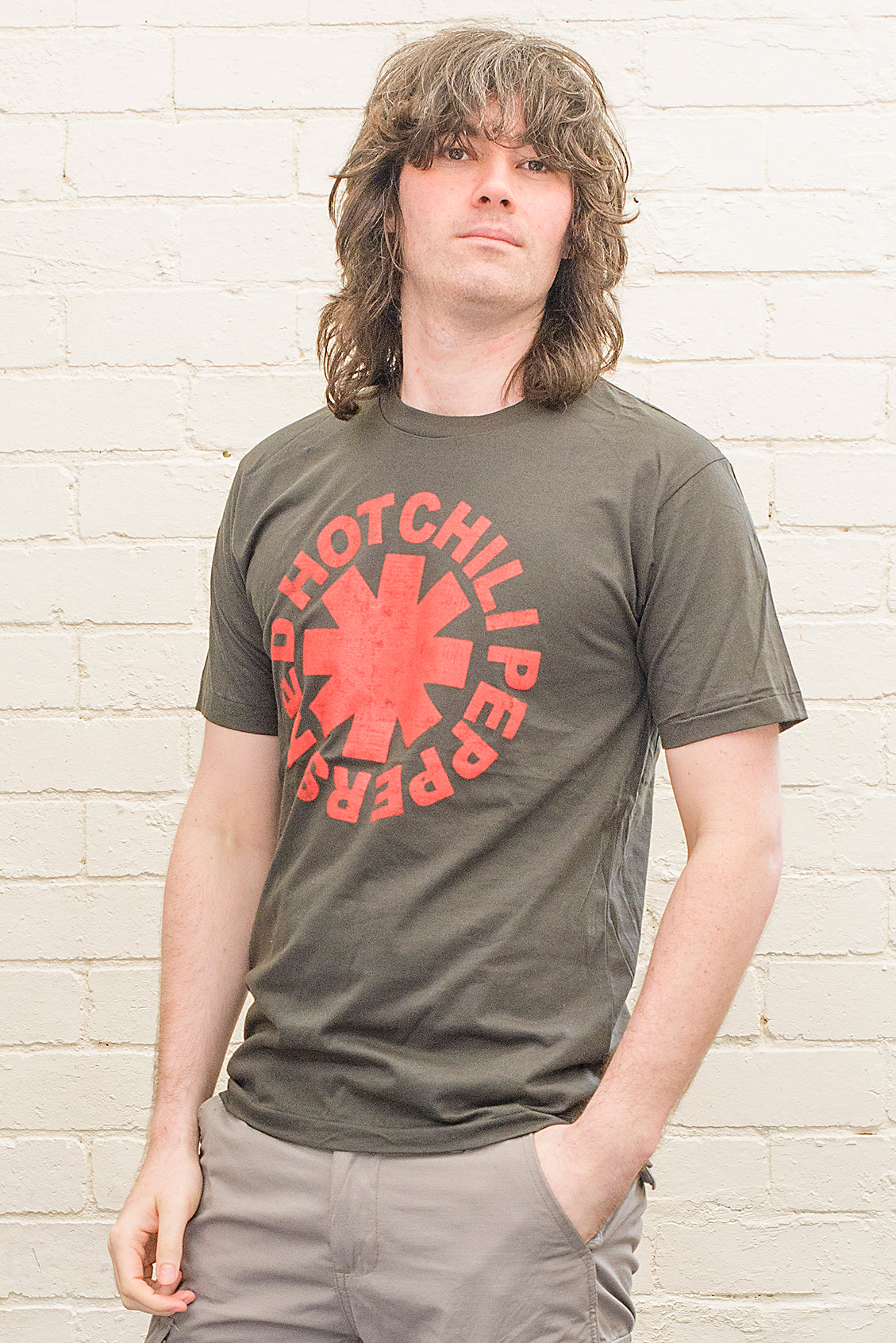 model wearing black cotton t-shirt with red hot chili peppers logo and band name printed on front