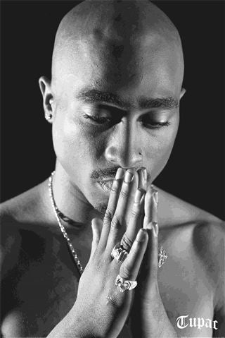 Black and white portrait of Tupac praying wearing a necklace and rings
